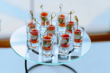 Kiraz domatesleri, taze otlar ve kremalı mozzarellayla dolu güzel düzenlenmiş shot bardakları. Yemek ve etkinlikler için mükemmel..