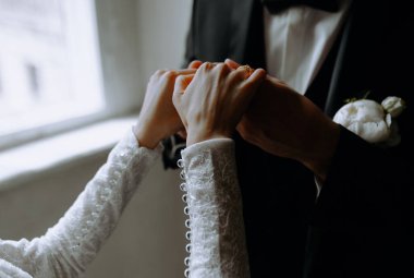 Bir çiftin elleri birbirine dolanmış alyansları değiş tokuş ederken, zarif bir ortamda sevgi ve bağlılık gösteriyorlar..