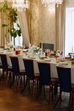 Taze çiçekler, mumlar ve nefis sofra takımlarıyla süslenmiş güzel bir yemek masası. Toplantılar ve kutlamalar için davetkar bir ortam yaratıyor..