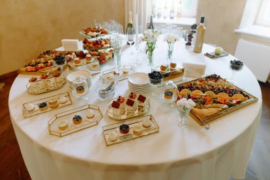 Enfes bir ziyafet masası. Taze meyveler, kremalı tatlılar ve şık sofra takımlarıyla dolu. Her bayram için idealdir..