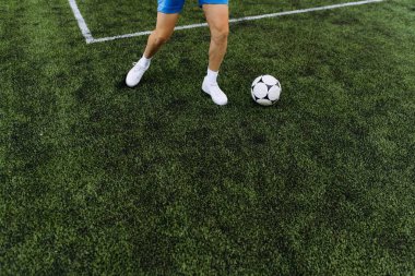 Sentetik çim tarlasında futbol topu süren bir oyuncunun dinamik hareketi, atletizm ve yeteneğini gösteriyor..