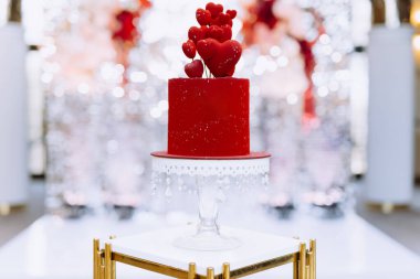 Kalp şeklindeki süslemelerle süslenmiş güzel bir kırmızı pasta, romantik kutlamalar ve özel etkinlikler için mükemmel..