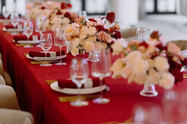 Bir restoranda servis edilen ziyafet. Enfes çiçek süslemeleri ve zarif sofra takımları olan güzel bir yemek masası. Düğünler ve resmi etkinlikler için mükemmel..