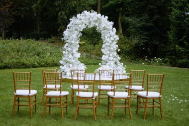 Çiçekli kemer ve iyi düzenlenmiş sandalyelerin olduğu çarpıcı bir açık hava düğün yeri romantik bir tören için mükemmel..