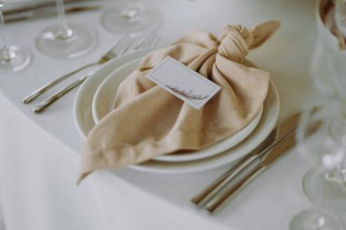 Düğümlü bir peçete ve şık bulaşık takımına yerleştirilmiş güzel bir masa takımı. Düğünler ve resmi yemekler için mükemmel..