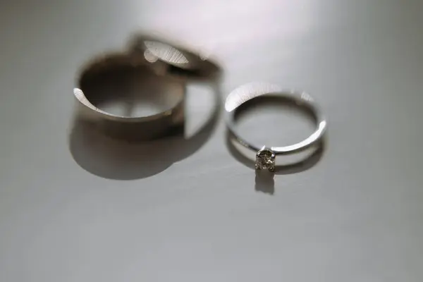 Güzel düğün ve nişan yüzükleri zarif bir şekilde parlak bir yüzeye uzanır, yumuşak ışığı yansıtır, aşkı ve bağlılığı sembolize eder..