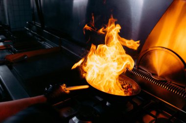 Mutfak sanatlarında dramatik bir an. Kızartma tavasından çıkan alevler yüksek enerjili yemek pişirmenin heyecanını gözler önüne seriyor..