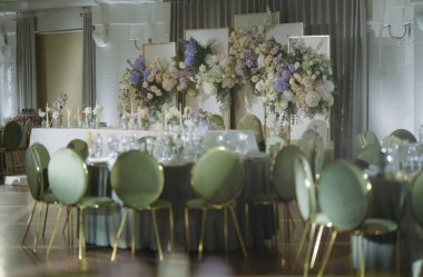 Nefis bir düğün resepsiyonu. Muhteşem çiçek düzenlemeleri ve zarif yeşil koltuklar. Güzel dekore edilmiş bir yerde..