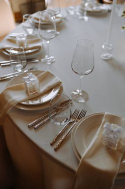 Şık bir masa kutlamaya hazır, içinde cam eşyalar, güzel yemek takımları, peçeteler ve dekoratif hediye kutuları var..