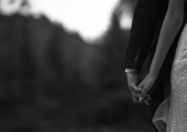 Bir çiftin düğün sırasında el ele tutuşup, yumuşak, bulanık doğal bir zemin oluşturduğu bir aşk ve bağlantı anı..