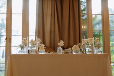 Beyaz güller ve mumlardan oluşan güzel bir masa. Sıcak bir ortamda özel bir toplantı için mükemmel..