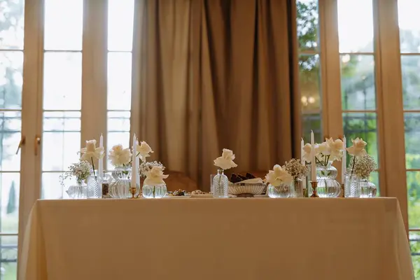 Beyaz güller ve mumlardan oluşan güzel bir masa. Sıcak bir ortamda özel bir toplantı için mükemmel..