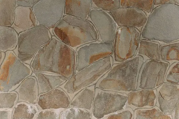 Çeşitli şekilleri ve toprak tonlarını gösteren, tasarım ve mimari arka planlar için mükemmel bir taş duvar görüntüsü..