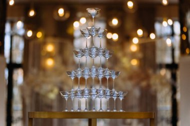 Şampanya kadehlerinden yapılmış çarpıcı bir cam kule. Sıcak bir arka planı olan zarif bir vitrin. Kutlamalar ve özel etkinlikler için ideal..
