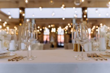 Kristal bardaklar, altın çatal bıçaklar ve sofistike bir yemek atmosferi yaratan şık bir masa dekoru..