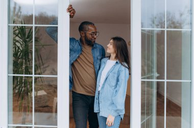 Sevgi dolu bir çift pencerenin kenarında durur, gülümsemelerini paylaşır ve şık yaşam alanlarında birbirlerinin arkadaşlığından zevk alırlar..