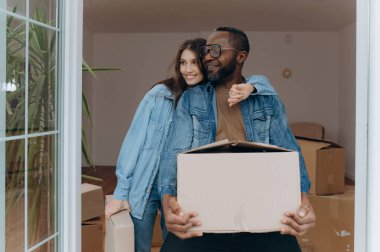 Kutuları dışarı taşırken, değişim ve heyecan anında birbirlerini kucaklayan neşeli bir çift yeni evlerini kutluyorlar..