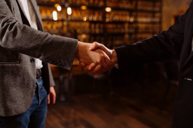 İki profesyonel, karmaşık bir bar ortamında anlaşma ve ortaklığı sembolize ediyor..