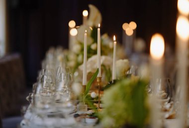 Mumlar, cam eşyalar ve taze çiçekler içeren güzel bir yemek masası. Zarif bir akşam yemeği ya da kutlama için mükemmel..