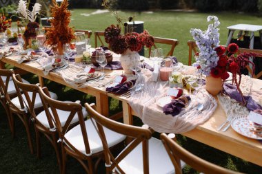 Renkli çiçekler, cam eşyalar ve gurme yiyeceklerden oluşan güzel bir açık hava yemek masası. Toplamak için mükemmel..