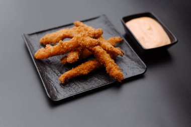 Lezzetli bir sosun yanında bir tabak kızarmış altın çubuk. Atıştırmalık veya aperatif olarak mükemmel..