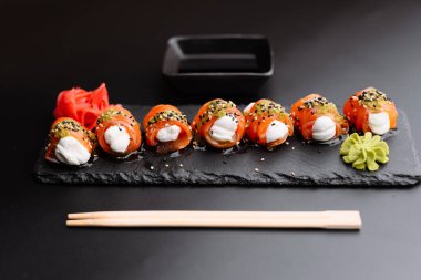 Krem peynirle kaplı lezzetli suşi ruloları, susam tohumları, wasabi ve turşulu zencefil ile servis edilir..