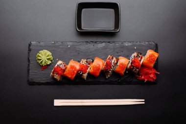 Wasabi ile süslenmiş nefis suşi dürümleri, soya soslu siyah bir tabakta servis edilir..