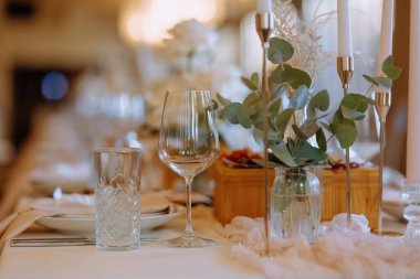 Güzel düzenlenmiş bir masa, cam kaplama, zarif peçeteler, ve yemyeşil, düğün ya da şenlik için mükemmel..