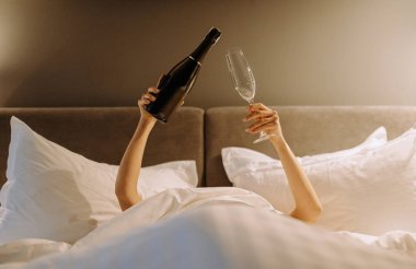 Şampanyayla bardağın olduğu rahat bir kutlama sahnesi. Yataktaki lüks anlar için mükemmel..