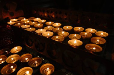 Süslü bir tutacakta yanan mumların sakin bir sahnesi loş bir ortamda huzurlu bir ortam yaratıyor..
