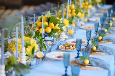 Mavi camdan yapılmış güzel bir yemek masası ve canlı limon süslemeleri. Şenlikli bir toplantı ya da etkinlik için mükemmel..
