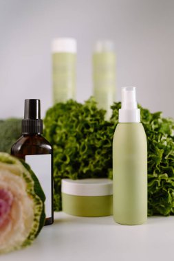 Taze yeşil marulla sergilenen organik cilt bakımı şişeleri ve kavanozlar, doğal güzellik ve refahı teşvik eder..