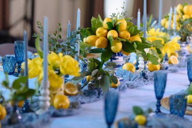 Mavi cam süslemeli canlı limon süsü ve mumlar taze, şenlikli bir masa atmosferi yaratır..