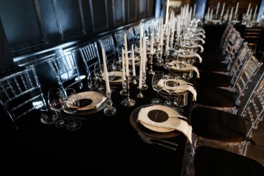 Şatafatlı resmi yemek masası, siyah dekor, cam süs ve lüks etkinlikler için uzun beyaz mumlar..