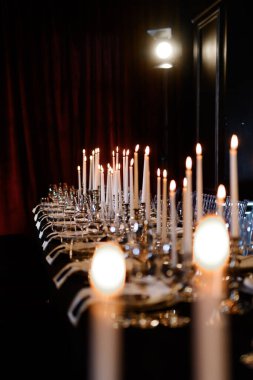 Parlayan mumlar, cam eşyalar ve tabaklar ile uzun resmi yemek masası, akşam kutlamaları için mükemmel..
