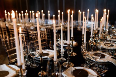 Uzun mumlar, cam eşyalar ve gümüş çatal bıçaklarla süslü resmi yemek masası. Zarif kutlamalar için mükemmel..