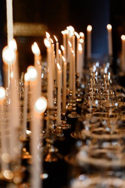 Sıralar dolusu parlak mum ve pırıl pırıl cam eşyalar sıcak, sofistike bir akşam yemeği partisi atmosferi yaratır..
