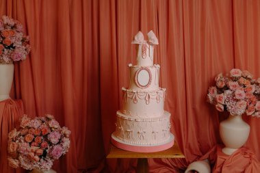 Gül vazolarıyla çevrili, süslü, pembe katlı pasta, düğünler ve kutlamalar için mükemmel..