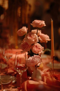 Mum ışığında romantik pembe güller özel akşam yemekleri için sıcak ve zarif bir ortam yaratır..