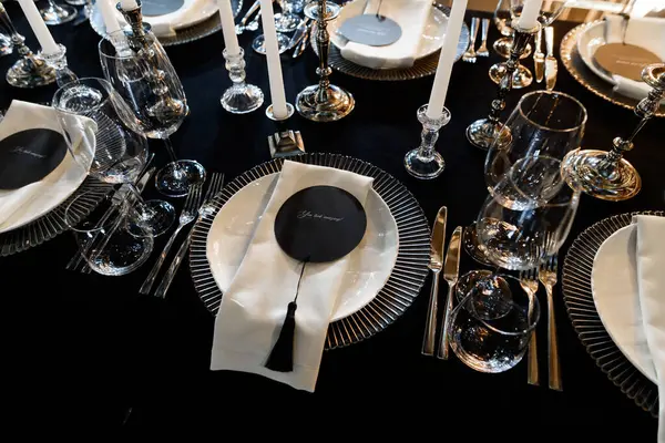 Siyah-beyaz temalı lüks resmi yemek masası, cam eşyalar, mumlar ve zarif yer kartları..