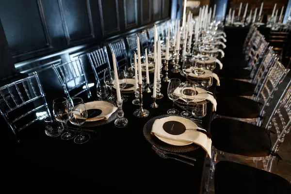 Şatafatlı resmi yemek masası, siyah dekor, cam süs ve lüks etkinlikler için uzun beyaz mumlar..