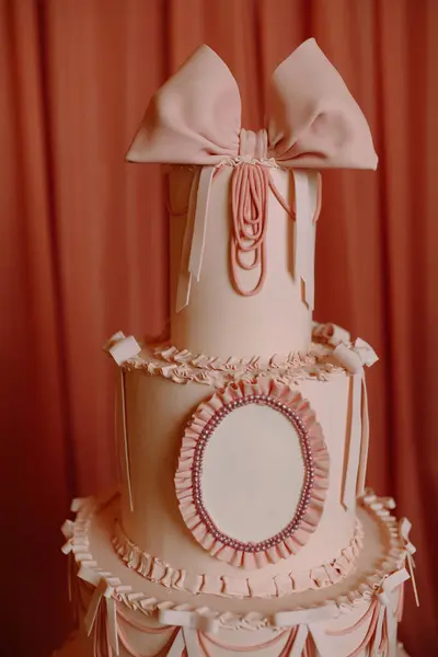 Zarif parti kutlamaları için mükemmel, büyük yay, fırfırlar ve incilerle süslü pembe pasta..
