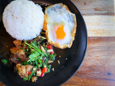 Üstünde kızarmış domuz göbeği, Tayland fesleğeni ve sahanda yumurta var.