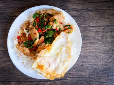 Üstünde kızarmış domuz göbeği, Tayland fesleğeni ve sahanda yumurta var.