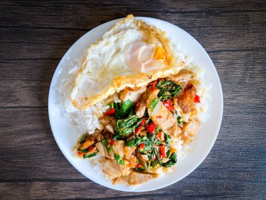 Üstünde kızarmış domuz göbeği, Tayland fesleğeni ve sahanda yumurta var.