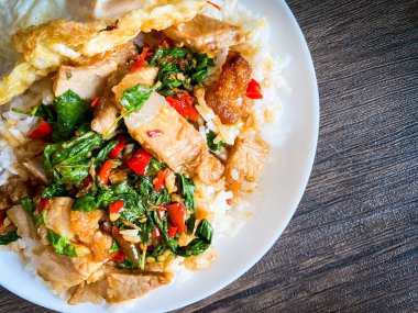 Üstünde kızarmış domuz göbeği, Tayland fesleğeni ve sahanda yumurta var.