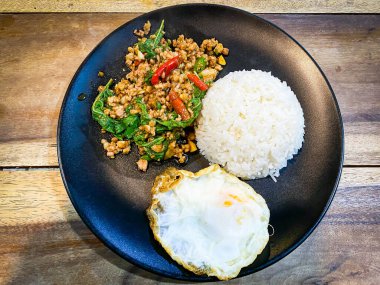 Üstünde kızarmış domuz göbeği, Tayland fesleğeni ve sahanda yumurta var.