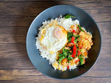 Üstünde kızarmış domuz göbeği, Tayland fesleğeni ve sahanda yumurta var.