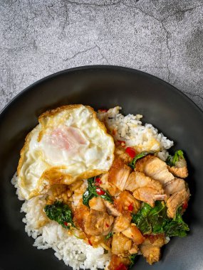 Üstünde kızarmış domuz göbeği, Tayland fesleğeni ve sahanda yumurta var.