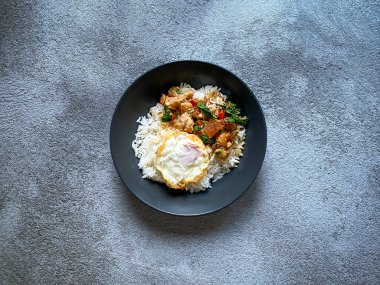 Üstünde kızarmış domuz göbeği, Tayland fesleğeni ve sahanda yumurta var.